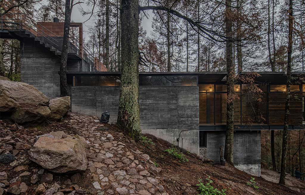 casa oruc adagiata pendio foresta cemento e legno